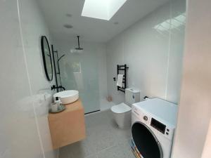 a white bathroom with a toilet and a washing machine at Waikanae Beach Abode in Waikanae +20 photos