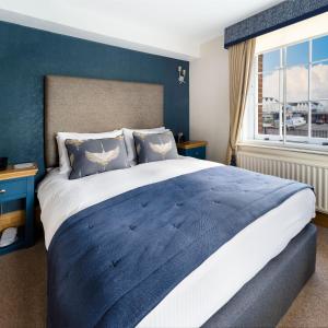 a bedroom with a large bed with blue walls and a window at Ennios Boutique Hotel in Southampton