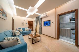 Red Sea Seasons Hotel Suites في جدة: غرفة معيشة مع أريكة زرقاء وتلفزيون