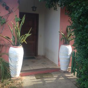 twee grote witte vazen voor een deur bij Casa Praia dos Amores Ferradurinha e Geriba in Búzios