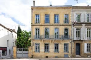 een oud bakstenen gebouw met ramen en een blauwe deur bij B&B Le Clos d'Argenson in Bergerac