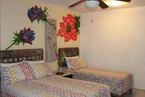1 Schlafzimmer mit 2 Betten und Wanddekorationen in der Unterkunft Casa Akbal B&B in Mérida