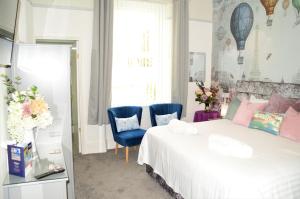a bedroom with a bed and two blue chairs at St Edmunds Guest House in Paignton