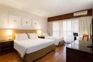 um quarto de hotel com duas camas e uma secretária em Mercure Sao Paulo Grand Plaza Paulista em São Paulo