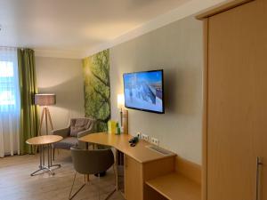 a hotel room with a desk and a tv on the wall at Hotel-Restaurant Haus Waldesruh in Borken