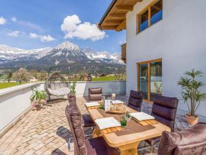 a patio with a table and chairs and mountains at Appartementhaus Tanja in Ellmau