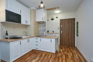 a kitchen with white cabinets and a wooden floor at Kawalerka z miejscem parkingowym w hali garażowej in Sopot