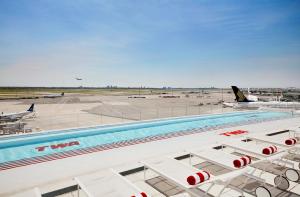 a swimming pool with lounge chairs and an airport at TWA Hotel at JFK Airport in Queens