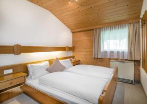 a bedroom with a large white bed with a window at Appartements Klausner in Altenmarkt im Pongau