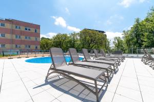 a row of chaise lounge chairs sitting on a patio at Apartamenty Fenomen - Baltic, Nadmorskie Tarasy, FREE PARKING, SWIMMING POOL, SAUNA AND OTHER! in Kołobrzeg