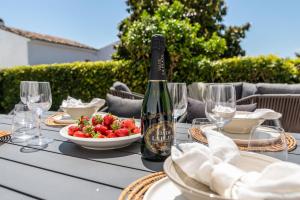 a table with a bottle of wine and a bowl of strawberries at Exclusive House located in Prime location in Marbella