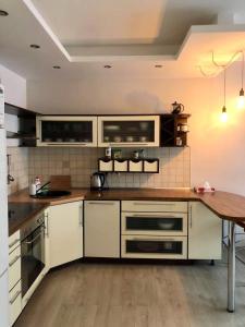 a kitchen with white cabinets and a wooden table at Vezas Apartment 3beds in Klaipėda