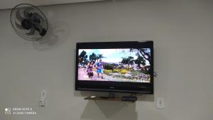 a flat screen tv on a wall with a fan at Flat familiar com ar,wi fi,cozinha e garagem in Aparecida