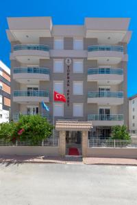 un gran edificio con una bandera roja delante de él en Toprak Apart Otel, en Antalya