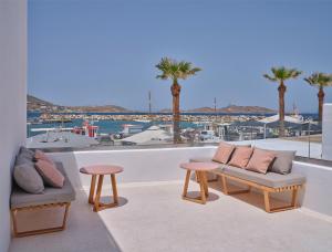 a balcony with two couches and two tables and palm trees at Karino Suite in Naousa