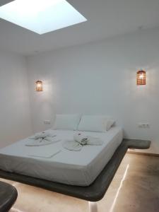 a white bed in a white room with two lights at Studio farma in Zefiría