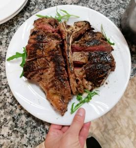 une personne tenant une assiette de steak sur une table dans l'établissement Hotel Reali, à Chianciano Terme