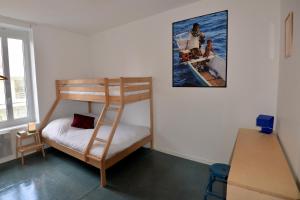 サン・ジル・クロワ・ド・ヴィにあるLES BAIGNEURSの二段ベッド1組、壁にポスターが備わる客室です。