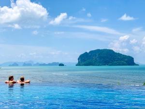 two people swimming in the ocean with an island in the background at Koh Yao Yai Village in Ko Yao Yai