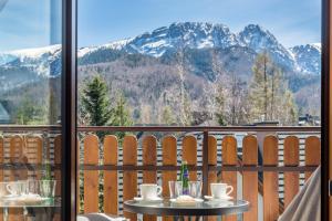 a table on a balcony with a view of mountains at Willa Zielony Zakątek in Zakopane