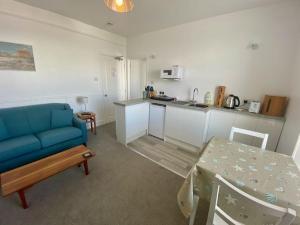 a living room with a blue couch and a kitchen at Coast Accommodation in St Ives