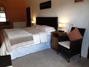 um quarto com uma cama grande e uma cadeira em Gortin Glen Guest House em Garvagh