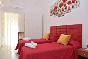 米諾利的住宿－Casa del Fauno，一间卧室配有两张带红色床单和毛巾的床。