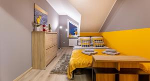Dormitorio amarillo con cama y escritorio en Apartament Spokojny, en Ustrzyki Dolne