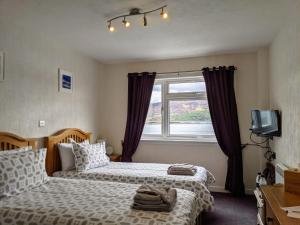 een slaapkamer met 2 bedden en een raam bij Rockvilla Guest House in Lochcarron