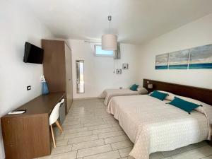 a bedroom with two beds and a desk and a tv at B&b il Patio in Villasimius