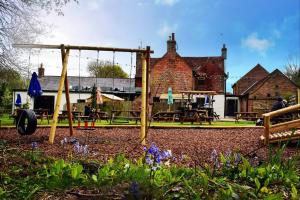 a playground with a swing and picnic tables and a building at The Roebuck Inn in Laughton