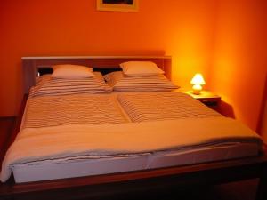 Cama grande en habitación con pared de color naranja en Delfin Apartman, en Sárvár