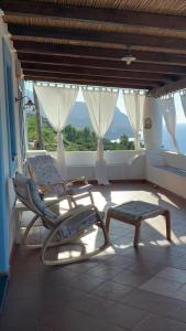 2 sillas y un banco en una habitación con ventana en La Casuzza Dei Re, en Malfa