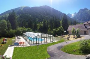 a glass building with a swimming pool in front of a mountain at Village vacances du Haut-Bréda aux 7 Laux in La Ferrière