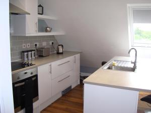 a kitchen with white cabinets and a sink at Spring Paddocks B&B in Furneux Pelham