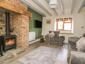 a living room with a fireplace and a couch and chair at Pollard Cottage in Northallerton
