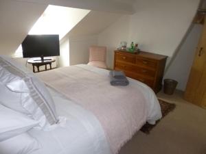 um quarto com uma cama branca, uma cómoda e uma televisão em Cranberry Cottage em Wallingford