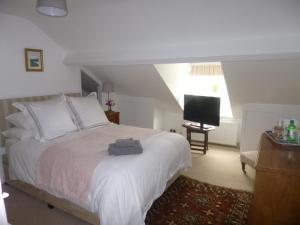 um quarto com uma cama branca e uma televisão em Cranberry Cottage em Wallingford