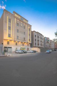 a large building with cars parked in a parking lot at Verdun Suites in Al Madinah