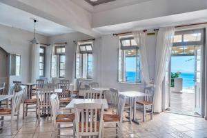 une salle à manger avec des tables et des chaises et l'océan dans l'établissement APOLLON PALACE, à Kinion