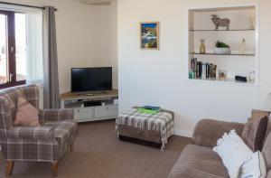 a living room with two couches and a tv at Greenfield Cottage in Thrumster
