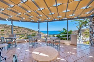 eine Terrasse mit Tischen und Stühlen und Meerblick in der Unterkunft APOLLON PALACE in Kini