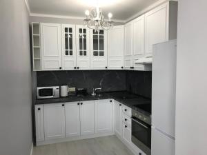 a white kitchen with white cabinets and a chandelier at Квартира 3-комнатная ЛЮКС in Sukhum +19 photos