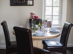 uma mesa de madeira com cadeiras e um vaso de flores em Lord High Admiral em Winchcombe