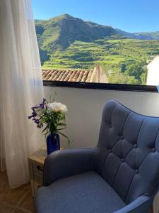 una silla azul y un jarrón con flores en una ventana en Casa El calado, en Viguera