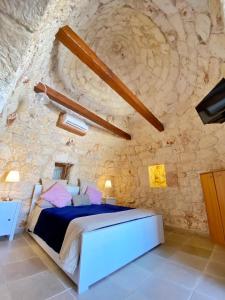 ein Schlafzimmer mit einem Bett in einer Steinmauer in der Unterkunft TRULLO DEL BOSCHETTO in Carovigno