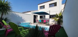 a patio with colorful chairs and a table and umbrella at Le Clos des Prés Carrés - La Maline - Piscine chauffée et salle de jeux in Sainte-Soulle