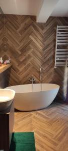 a bathroom with a white tub and a wooden wall at Apartament 31 Kozubnik joy&love in Porąbka