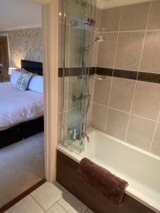 a bathroom with a shower and a tub with a bed at Treveighan Farmhouse in Saint Teath