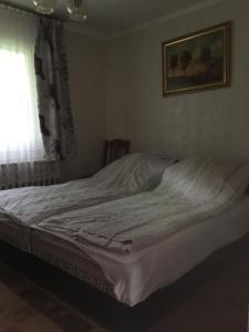 an unmade bed in a bedroom with a window at Kilátó úti Vendégház in Matrafured